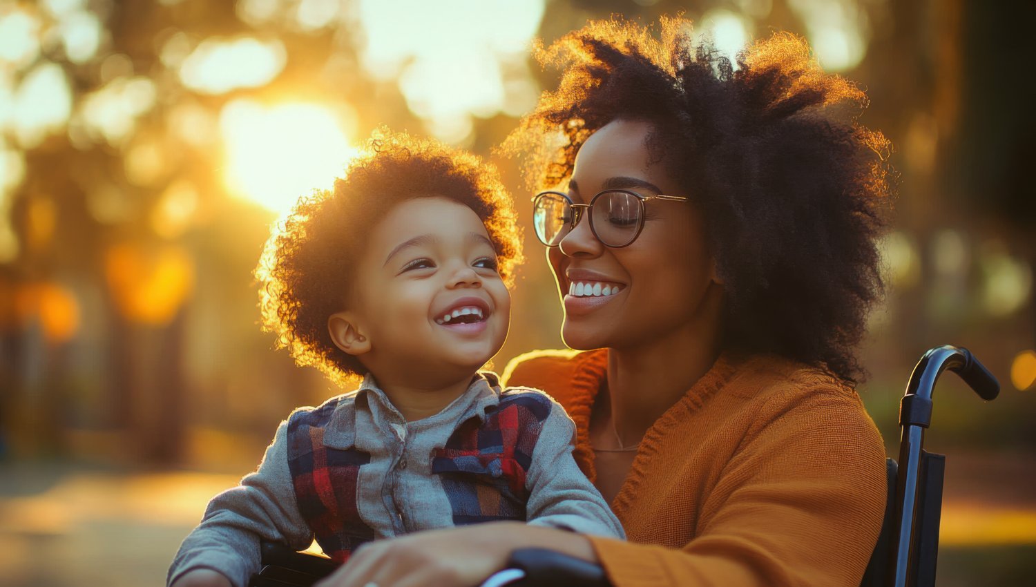 A mother and her child, who uses a wheelchair, sharing a joyful moment at sunset
